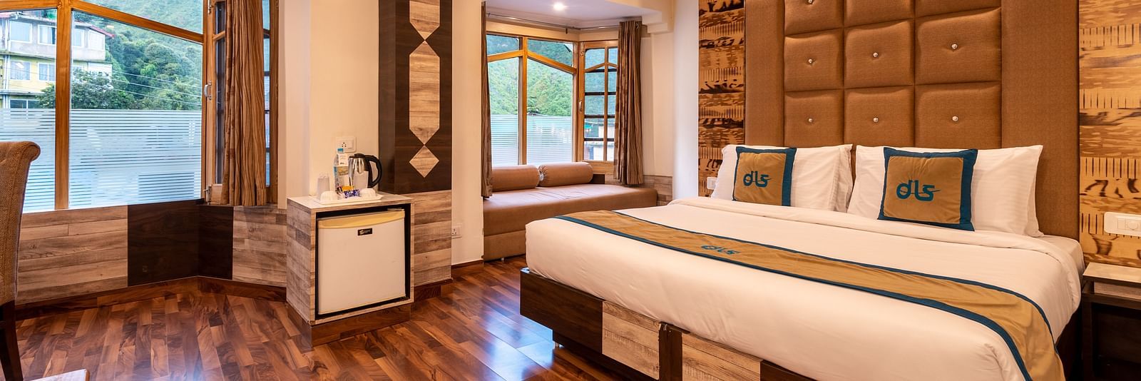 A hotel room in Bhagsunag featuring a large bed, wooden floors, a wooden ceiling, and windows with a view - DLS Meghavan Resort